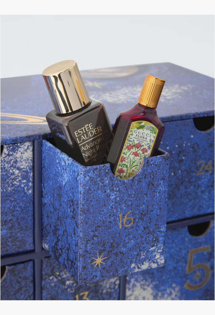 GLAM MODA beauty advent calendar featuring Estee Lauder Advanced Night Repair serum and Gucci Flora perfume bottle.