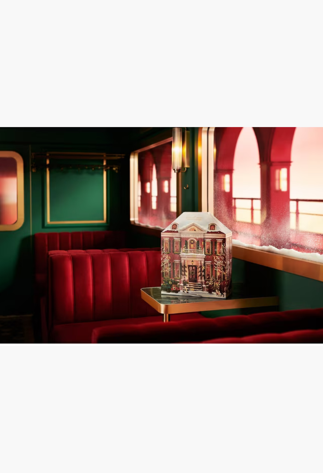 GLAM MODA Rituals Classic Advent Calendar shaped like a festive house sitting on a table in a luxury train carriage.