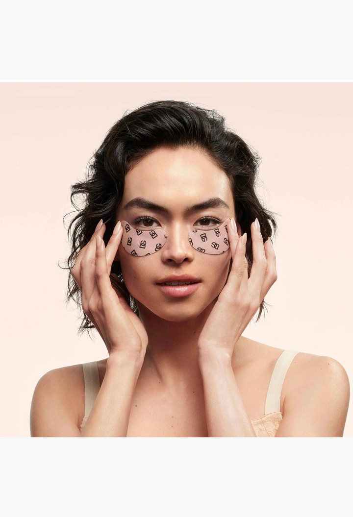 GLAM MODA Dolce & Gabbana caffeine eye patches with DG monogram on a woman's face for a refreshed look