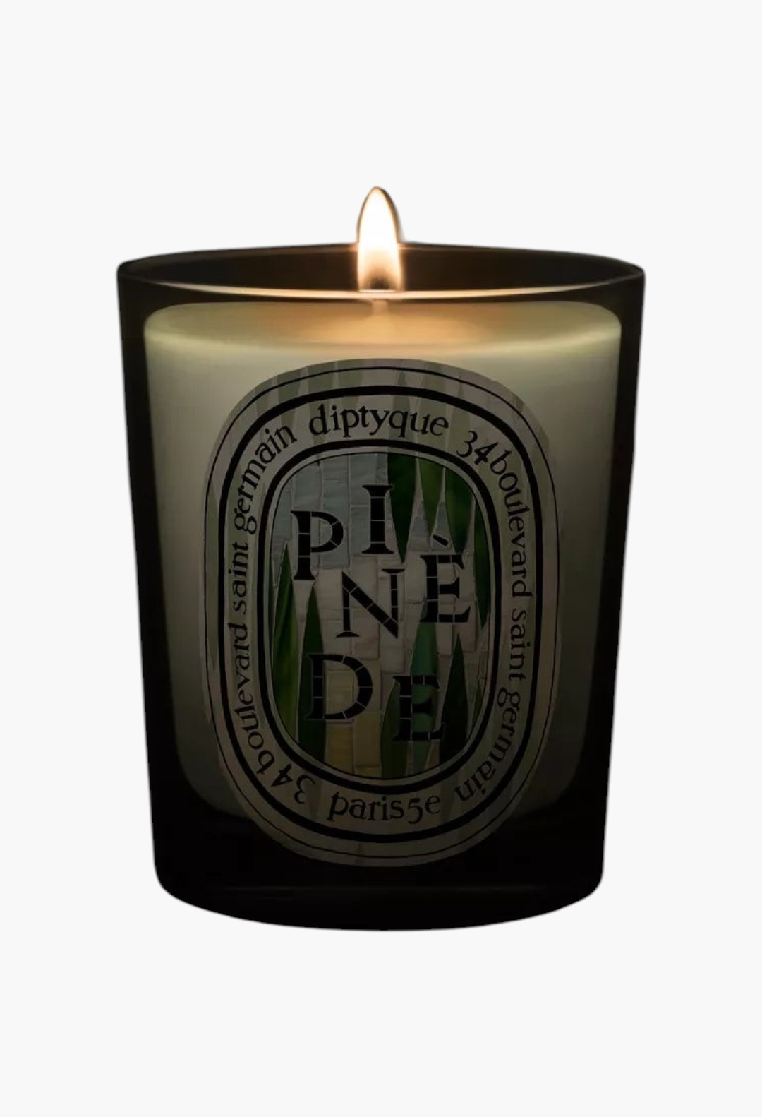 GLAM MODA Pinède scented candle in a black glass vessel with a lit wick, emitting a warm glow against a dark background.