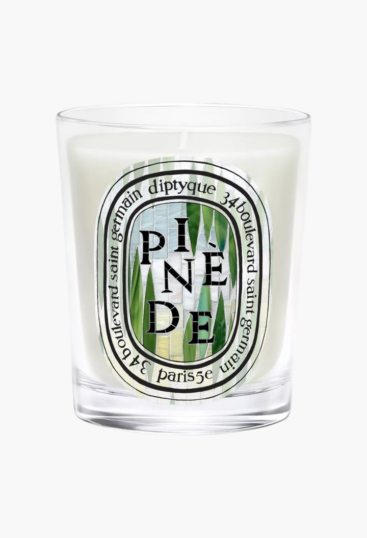 GLAM MODA Pinède scented candle in a clear glass vessel with a decorative oval label featuring pine needle motifs.