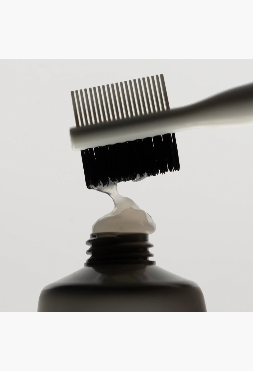 GLAM MODA dual-sided edge brush with nylon bristles and fine-tooth comb applying styling gel from a tube
