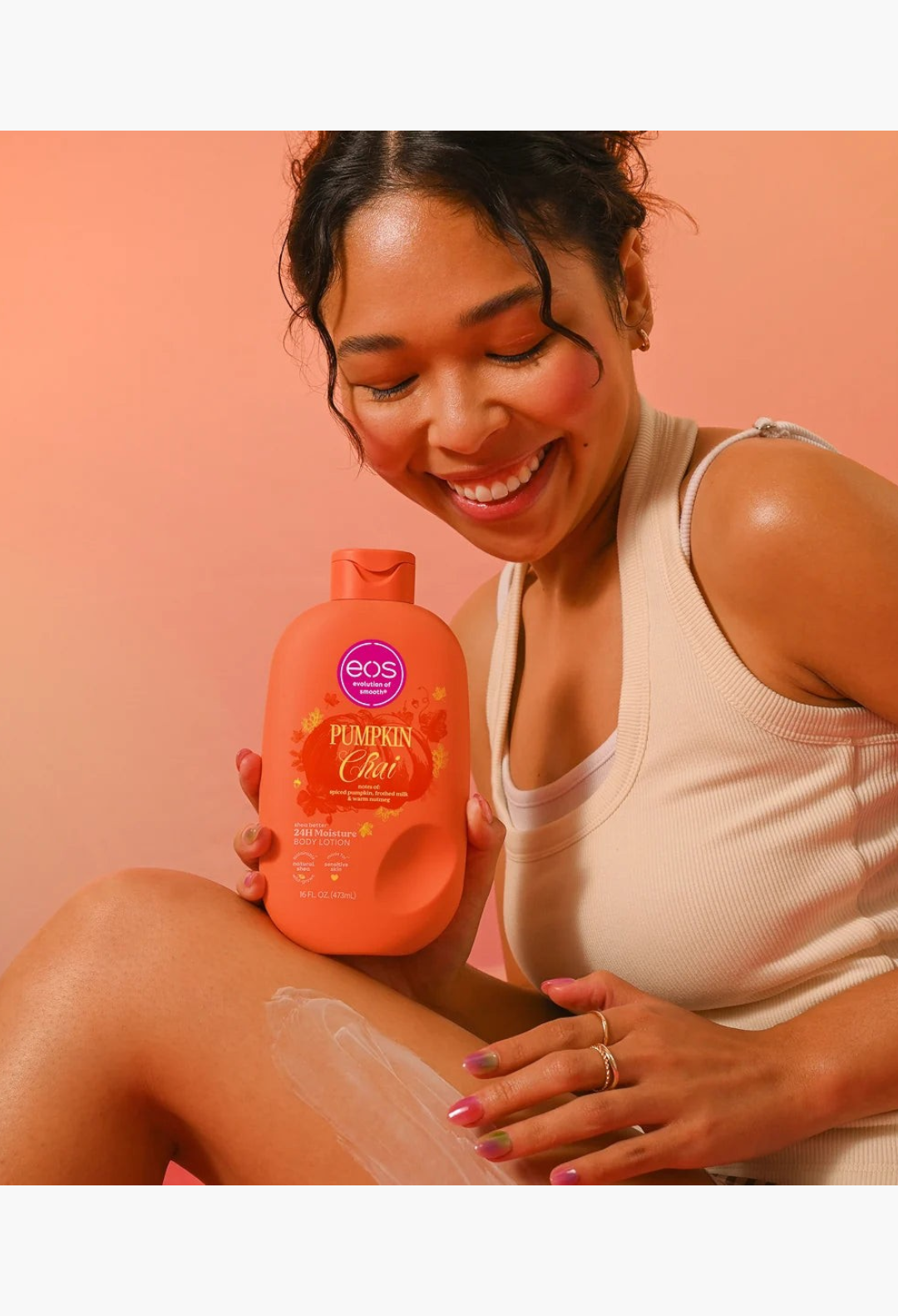 GLAM MODA model applying Pumpkin Chai body lotion from the Cozy Cravings bundle to her leg against a peach background