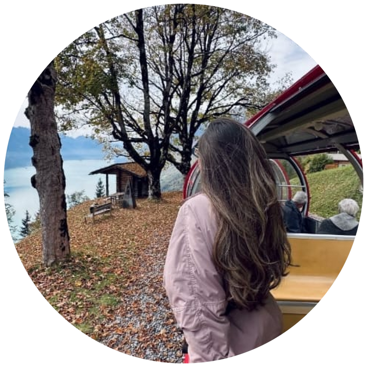 Woman looking at a scenic view from inside a vehicle with trees and a lake in the background.