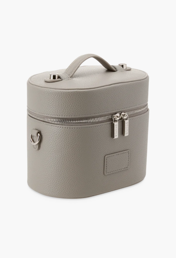 GLAM MODA oval toiletry case in grey vegan leather with a top handle, dual zipper closure, and shoulder strap rings.