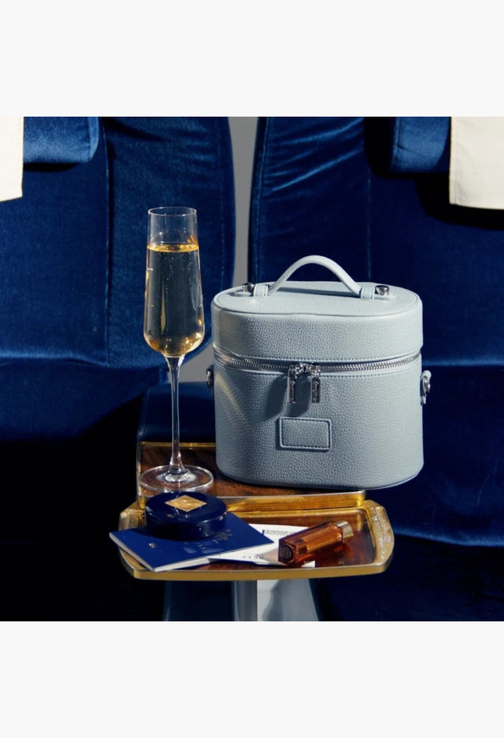 GLAM MODA oval vegan leather toiletry case in light blue with a top handle and double zipper on a gold tray.