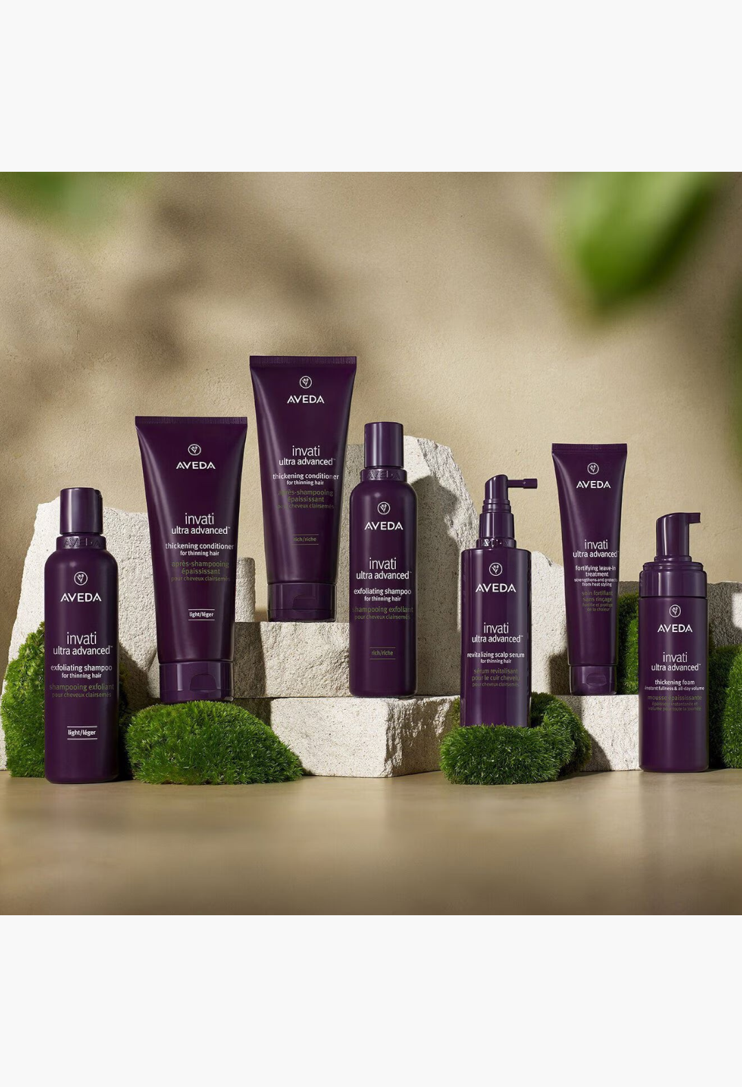 GLAM MODA Aveda Invati Ultra Advanced hair care system featuring purple bottles and tubes on stone platforms.