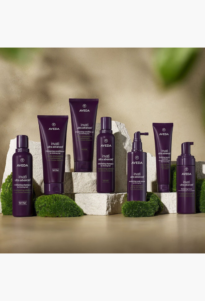 GLAM MODA Aveda Invati Ultra Advanced hair care system featuring purple bottles and tubes on stone platforms.