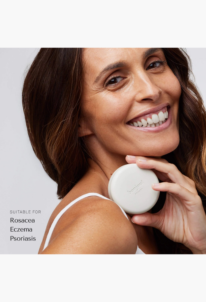 GLAM MODA smiling woman holding a round white Le Balm Quatre unscented solid serum container near her face