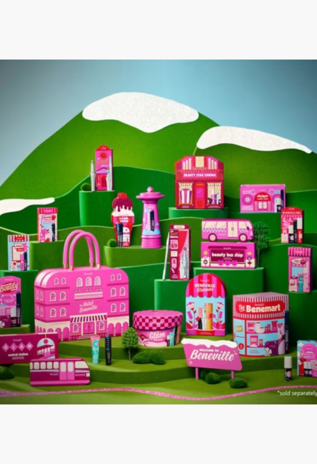 GLAM MODA Benefit The Hotel Beneville 24-piece beauty advent calendar featuring pink makeup boxes on green hills.