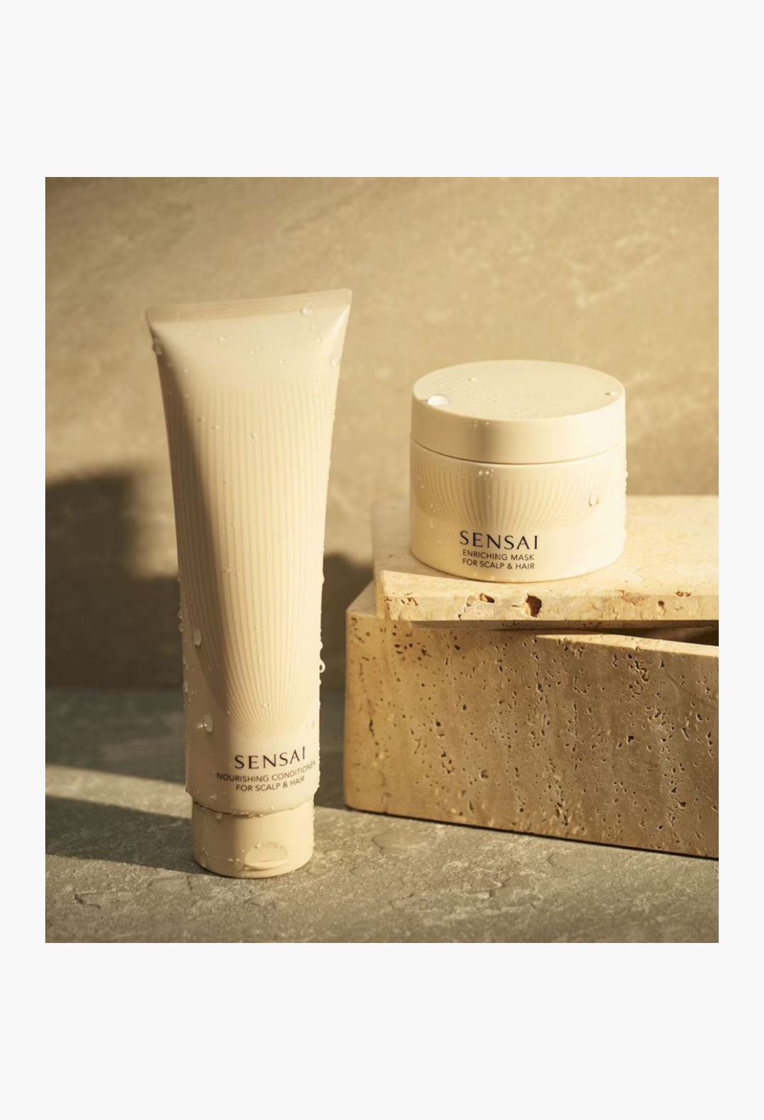 GLAM MODA SENSAI Nourishing Conditioner tube and Enriching Mask jar on stone blocks with water droplets