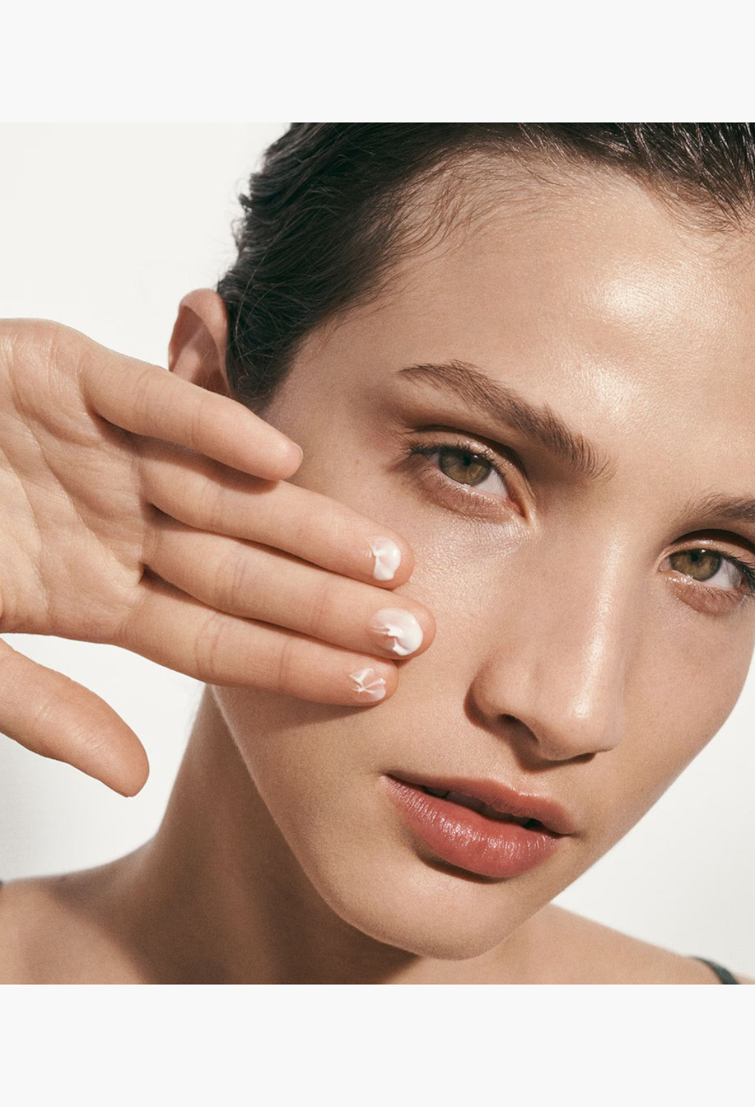 GLAM MODA The Moisturizing Soft Cream applied to a woman's cheek for a radiant and hydrated complexion
