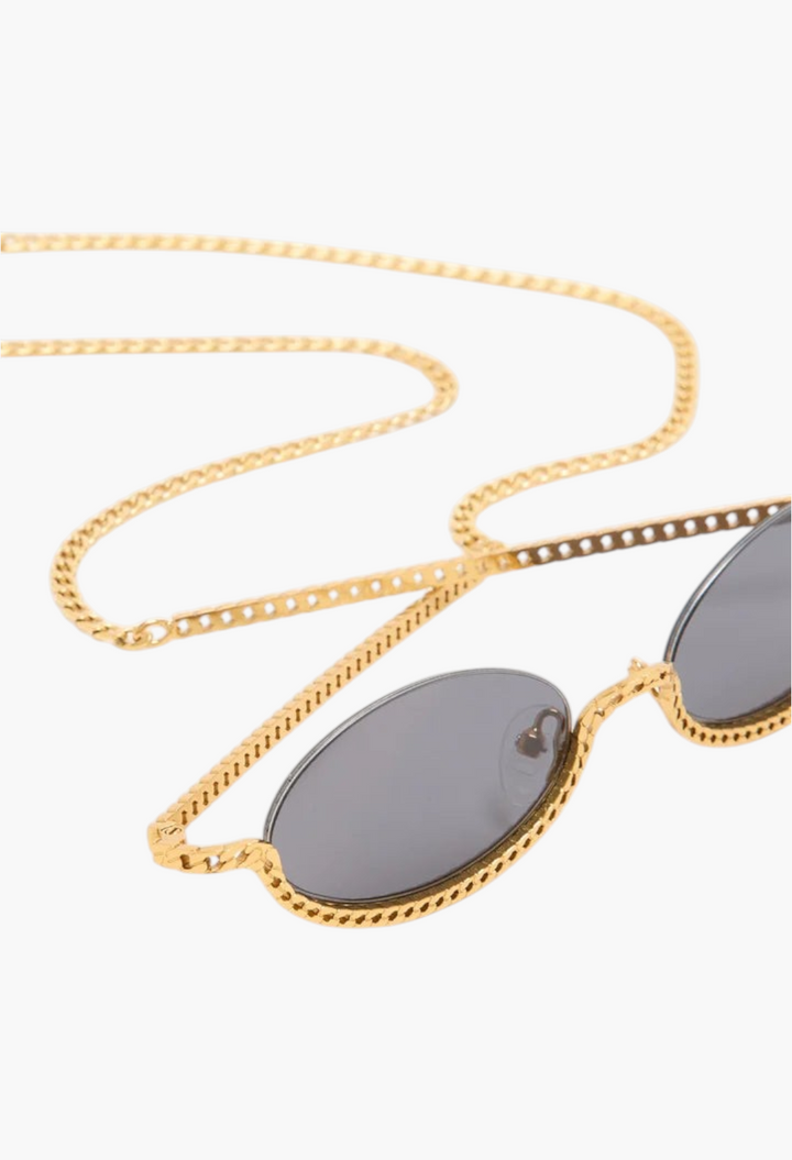 GLAM MODA Gaga sunglasses featuring gold metal sculptural frames with an integrated chain detail and dark lenses.
