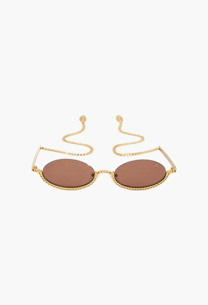 GLAM MODA Gaga sunglasses featuring gold metal sculptural frames, brown lenses, and decorative chain-link temple arms.