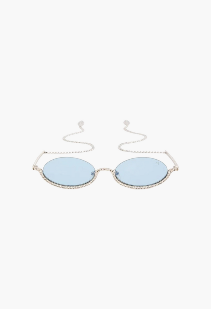 GLAM MODA Gaga sunglasses featuring sculptural gold metal frames with blue lenses and integrated chain detail.