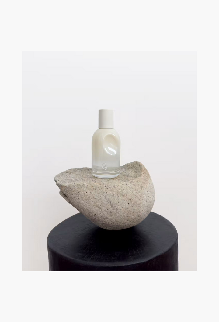 GLAM MODA Glossier You Doux eau de parfum in a minimalist glass bottle with a white cap resting on a natural stone