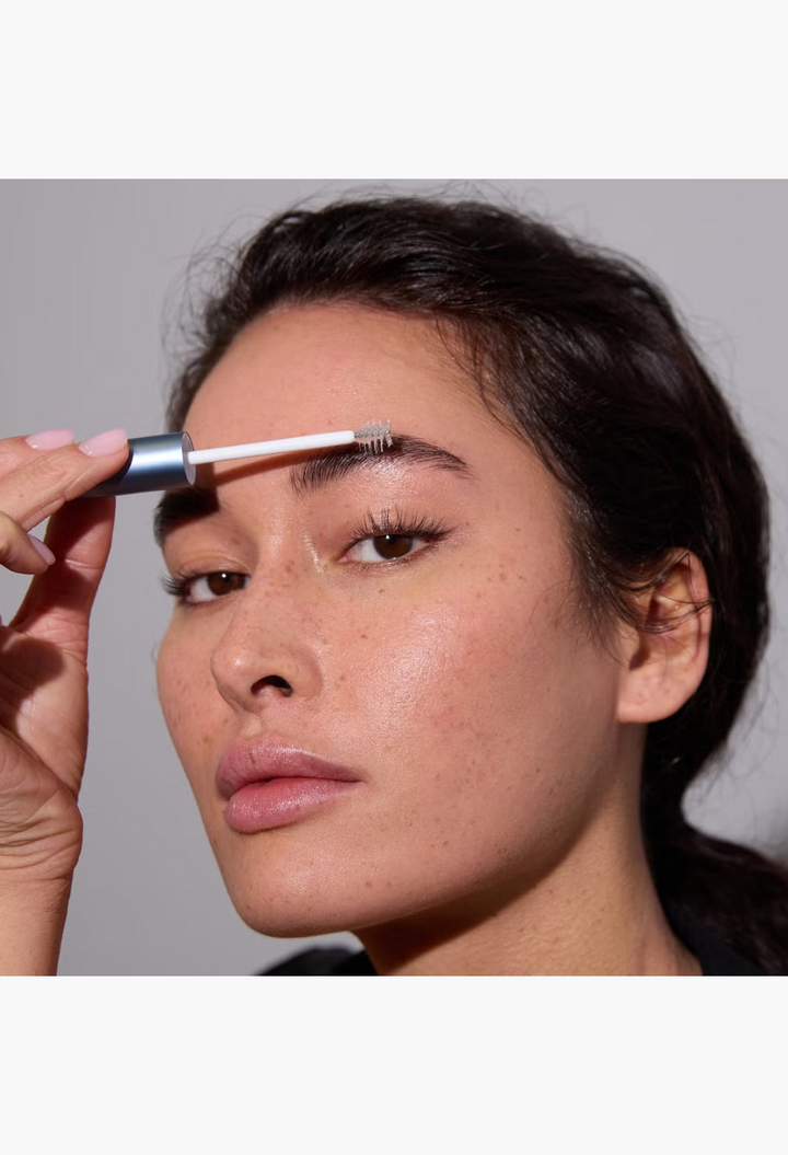 GLAM MODA model applying RapidBrow eyebrow enhancing serum with a spoolie brush for fuller and thicker arches