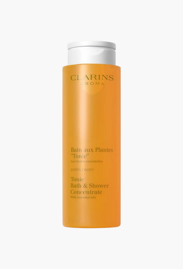 GLAM MODA Clarins Tonic Bath & Shower Concentrate in an orange bottle with a white cap for invigorating body cleansing.