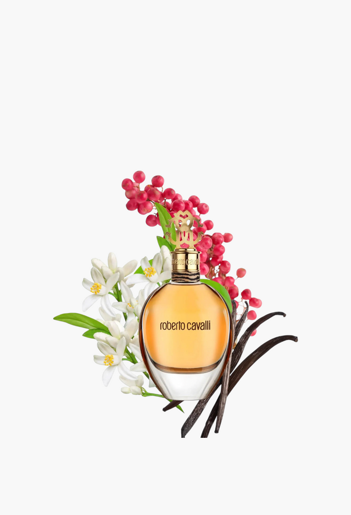 GLAM MODA Roberto Cavalli EDP perfume bottle surrounded by pink berries, orange blossoms, and tonka bean pods.