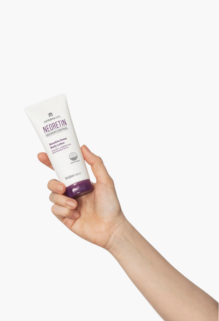 GLAM MODA Neoretin Discrom Control Sensitive Areas Body Lotion tube held in a hand against a white background.