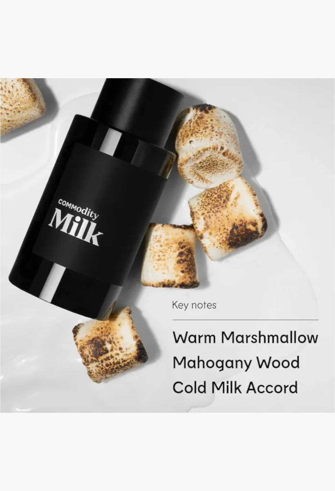 GLAM MODA Commodity Milk perfume bottle next to three toasted marshmallows on a plain white background