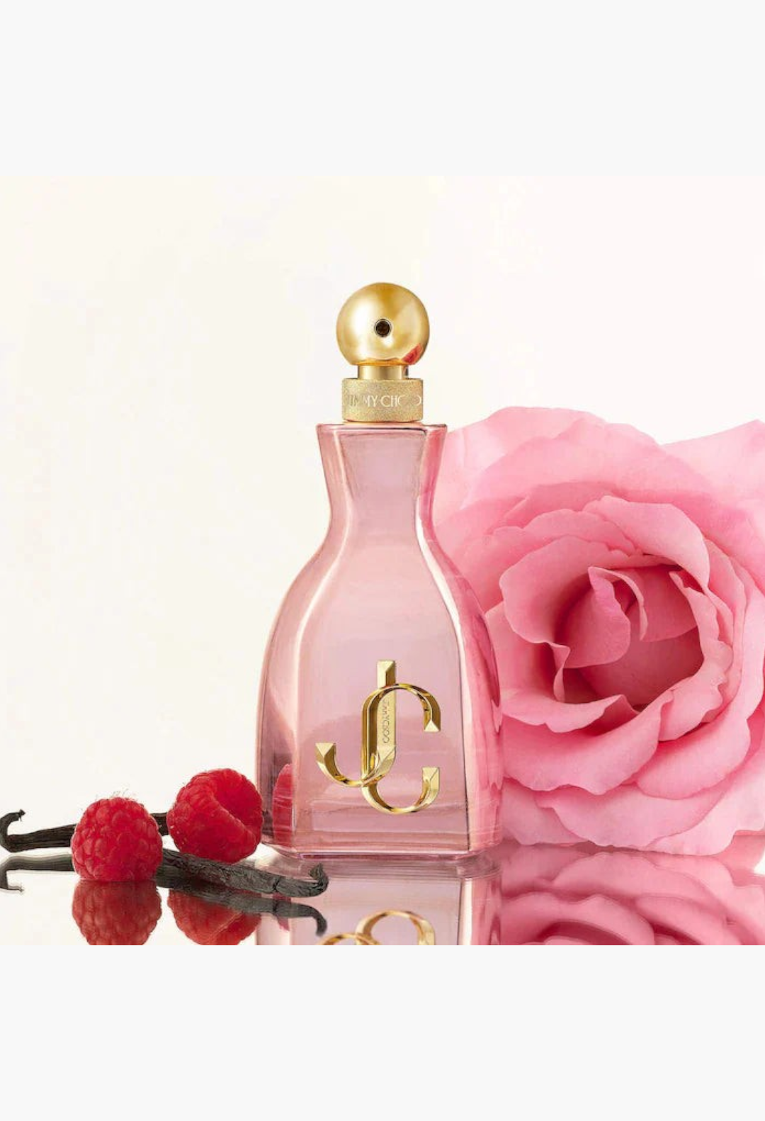 GLAM MODA perfume bottle with pink glass, gold cap, and logo, displayed with a pink rose, raspberries, and vanilla beans.