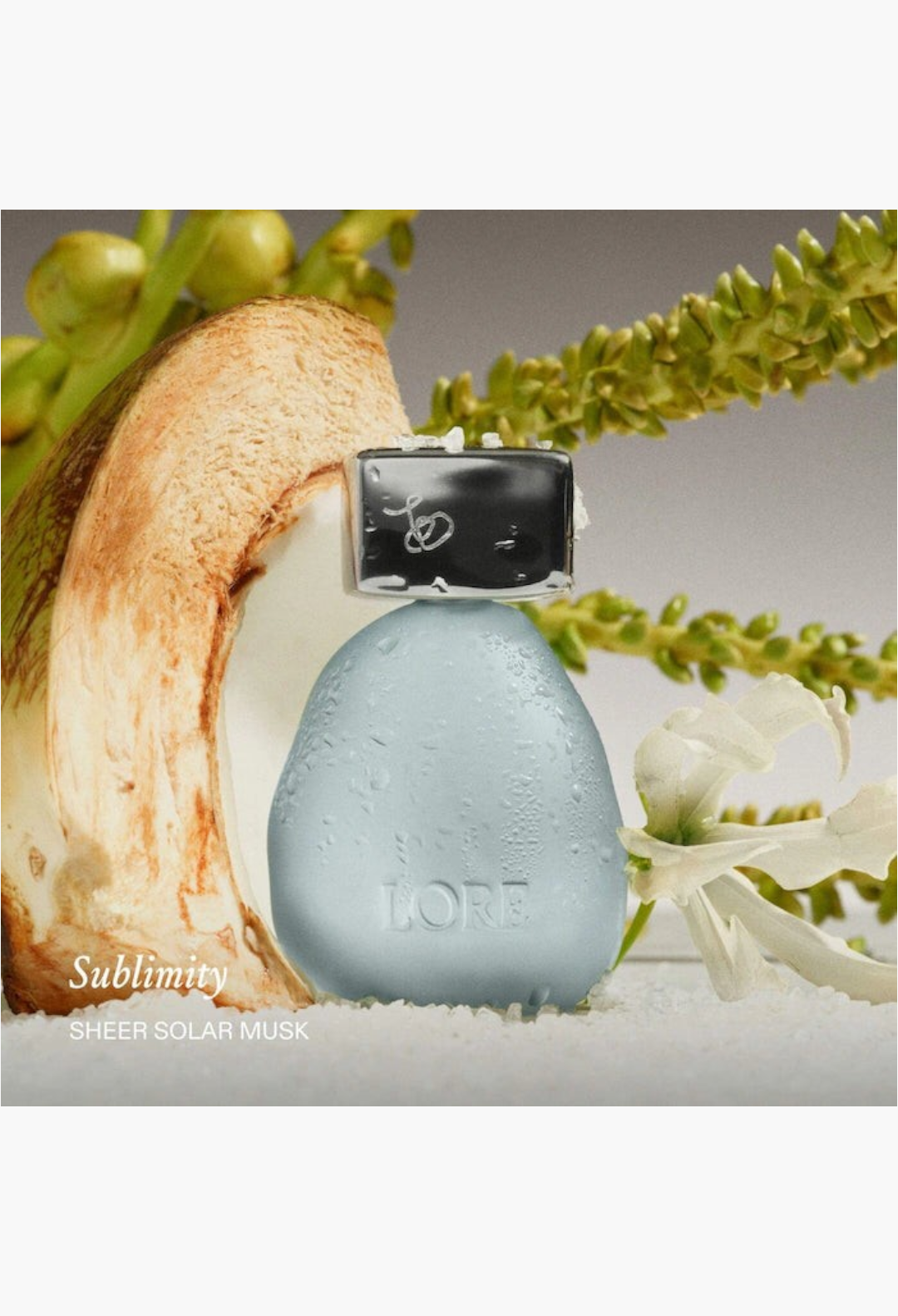 GLAM MODA Lore Sublimity Sheer Solar Musk perfume bottle with coconut and tropical flower accents on a white surface.