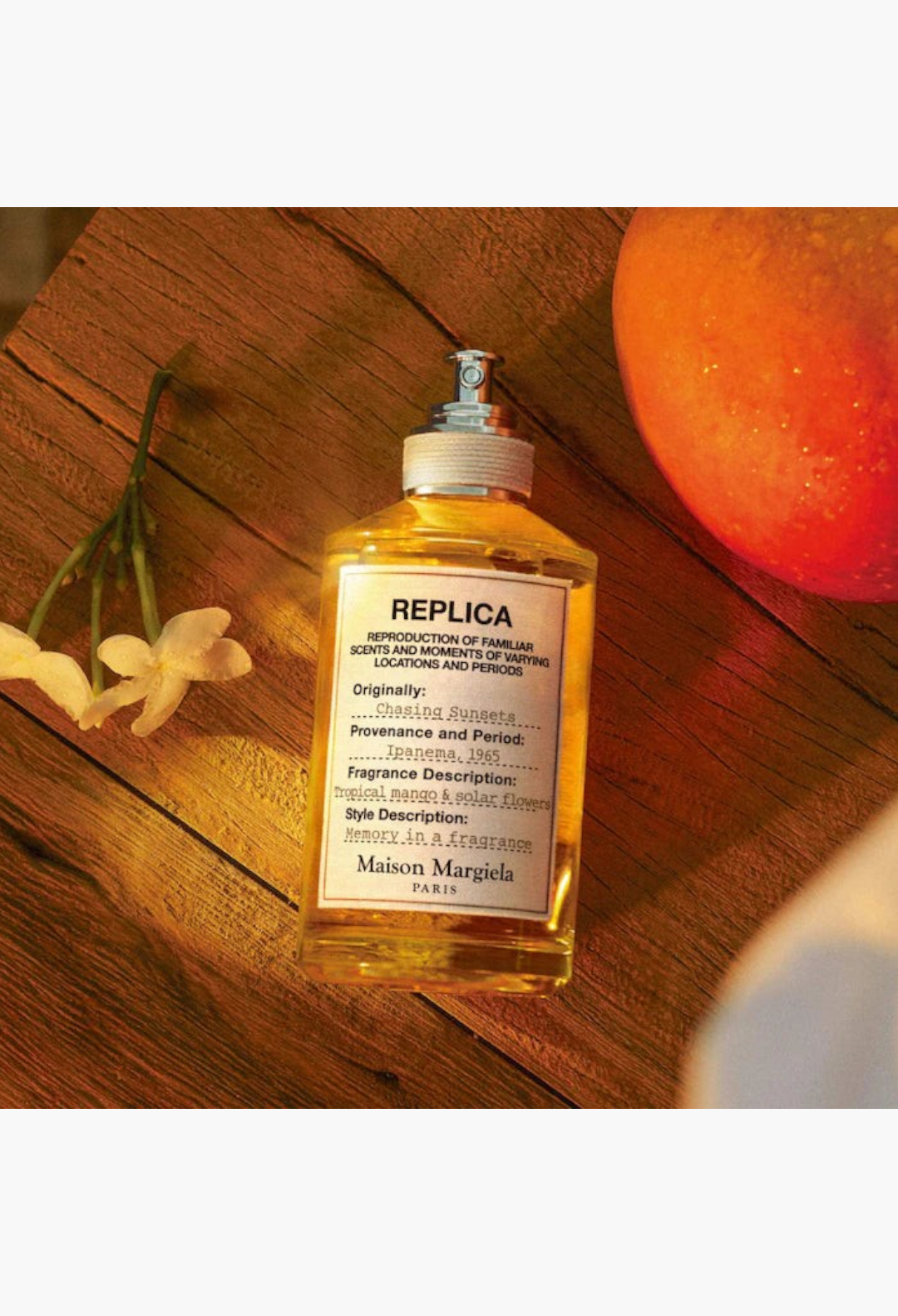 GLAM MODA Maison Margiela Replica Chasing Sunsets perfume bottle with golden liquid and small yellow flower sprig