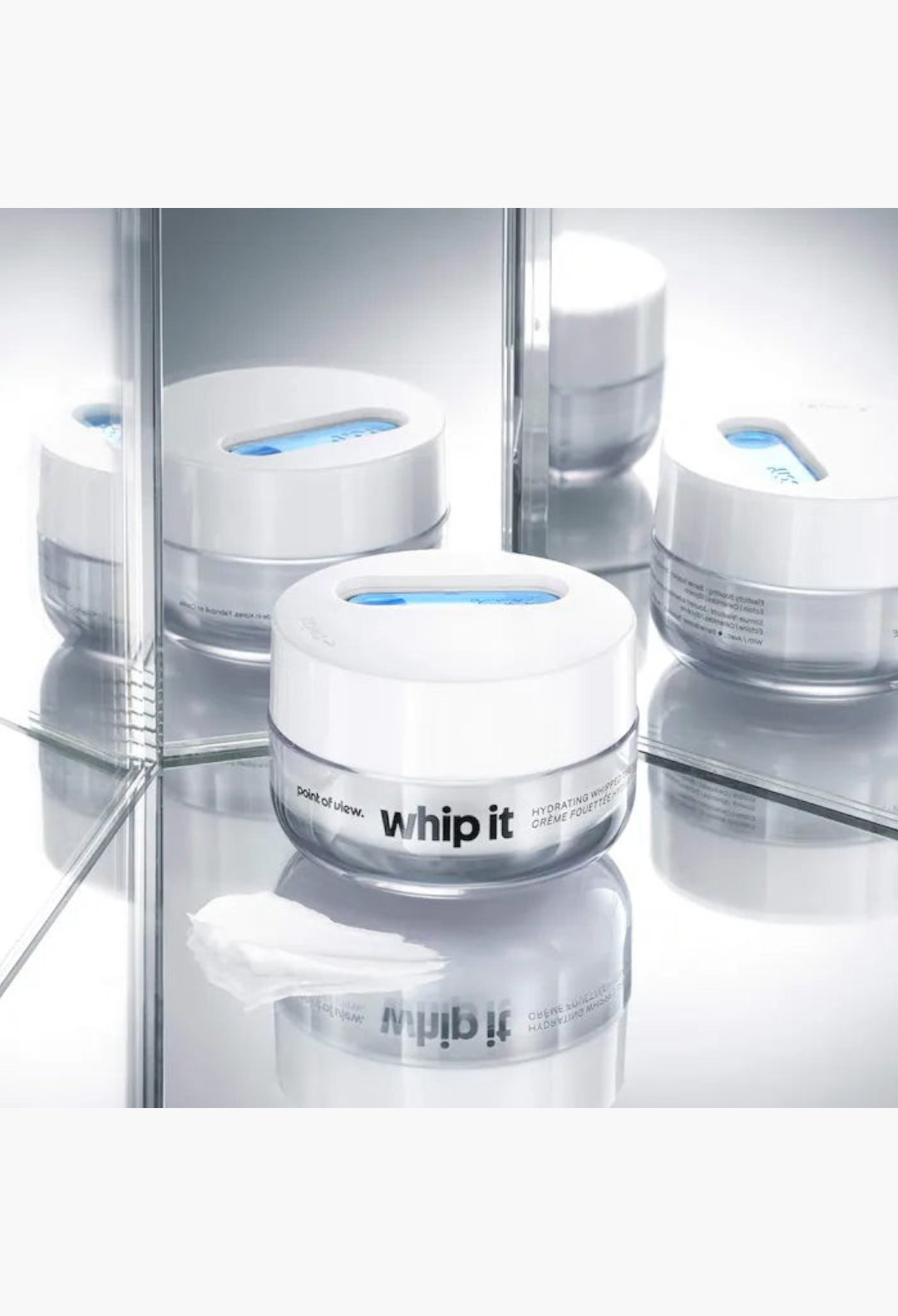 GLAM MODA Whip It hydrating whipped cream jar with blue spatula on a reflective surface for skin barrier support.