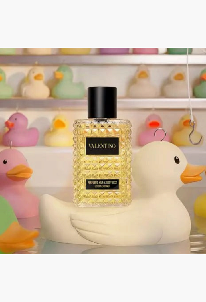 GLAM MODA Valentino Born In Roma Golden Coconut hair and body mist bottle resting on a decorative rubber duck