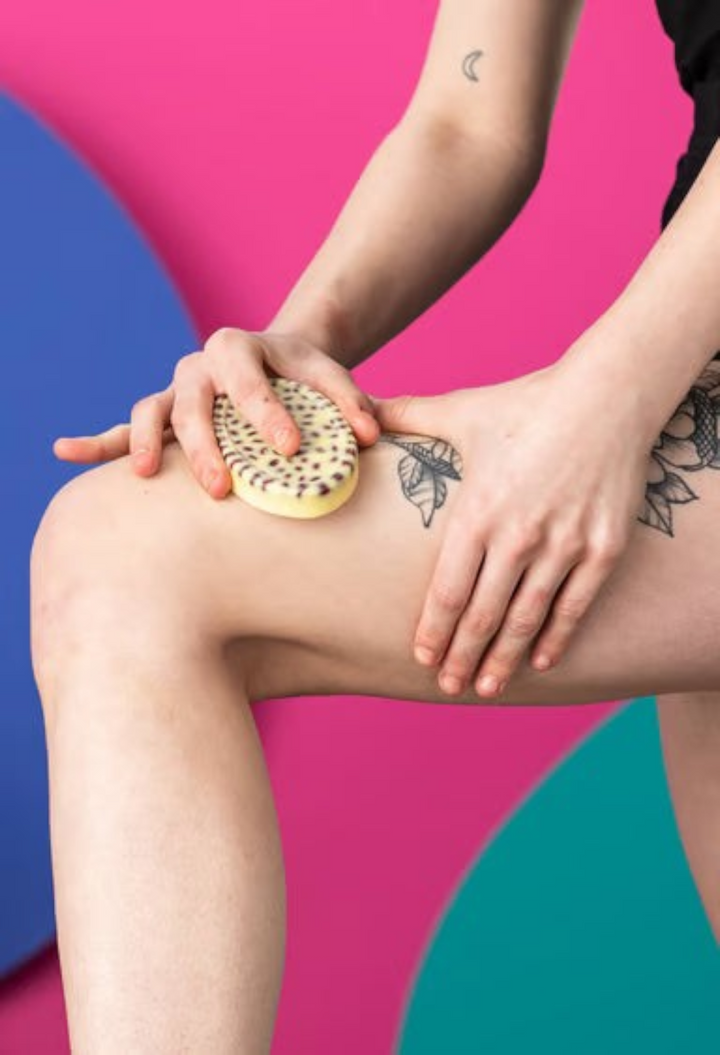 GLAM MODA Wiccy Magic Muscles massage bar with aduki beans being used on a leg against a vibrant colorful background